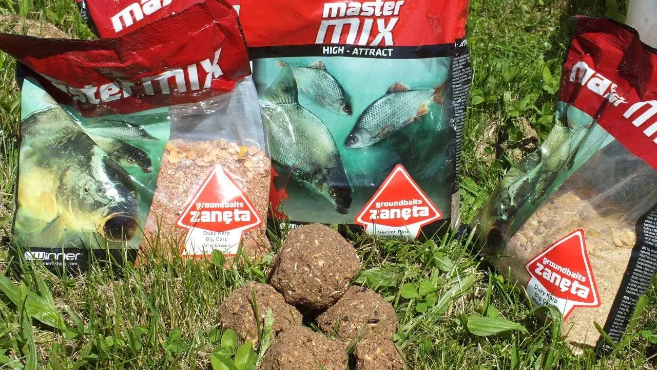 Kilka opakowań zanęta wędkarska 10kg i kulki proteinowe na trawie.