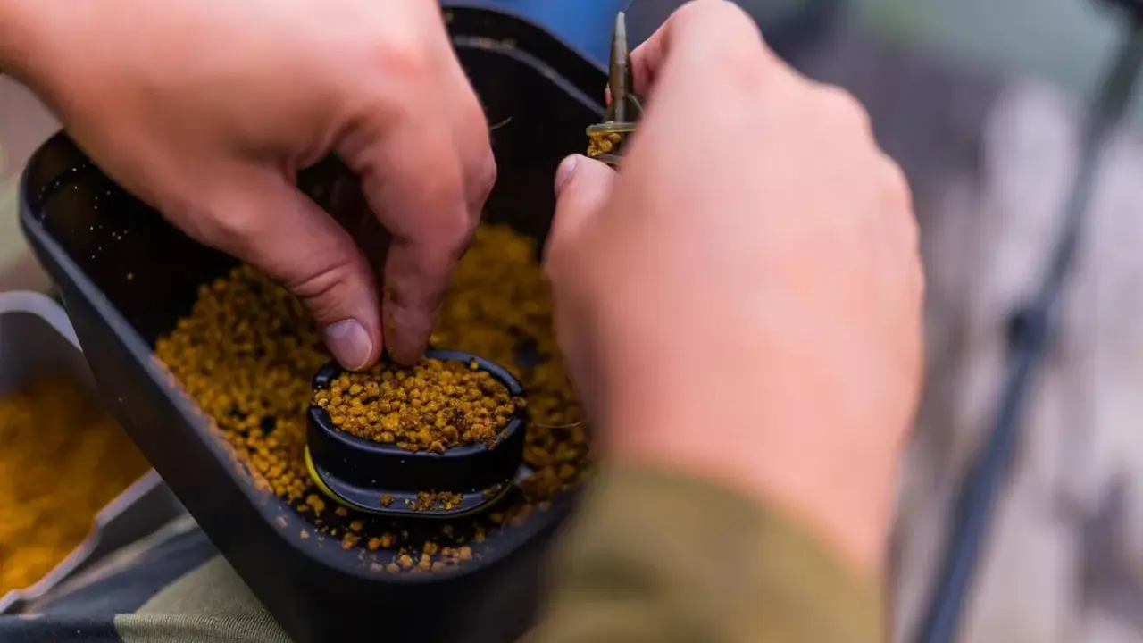 Wędkarz nakłada na haczyk drobny pellet, przygotowując się do połowu. Jaki pellet na haczyk będzie najlepszy?