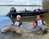 Dwóch wędkarzy z gigantycznym sumem w wodzie. Pytanie brzmi: jaki haczyk na suma pozwolił wyciągnąć taką rybę?