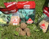 Kilka opakowań zanęta wędkarska 10kg i kulki proteinowe na trawie.