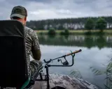 Wędkarz w kamuflażu czeka nad jeziorem. Czy to odpowiednia wędka do metody?
