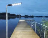 Drewniany pomost nad jeziorem, oświetlony lampami, zachęca do spaceru. Czy pomost nad jeziorem może być prywatny? Ten wygląda na dostępny dla wszystkich.