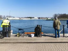 Dwóch wędkarzy z pozwoleniami na łowienie ryb czeka na branie nad wodą.