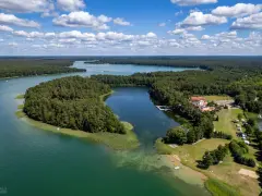 Malownicze jezioro Lechickie otoczone lasem, z hotelem i polem kempingowym na brzegu.
