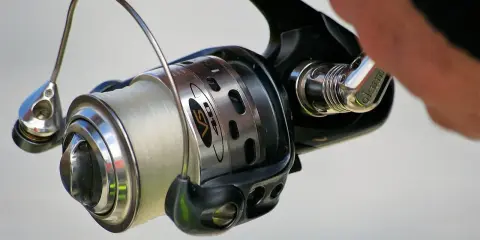 Kołowrotek spinningowy z nawiniętą żyłką, gotowy do akcji. Poznaj, jak zrobić spinning i łowić ryby!