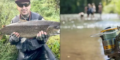 Wędkarz z dumą prezentuje imponującą rybę, być może płoć rekord polski. W tle widać rzekę i ludzi.