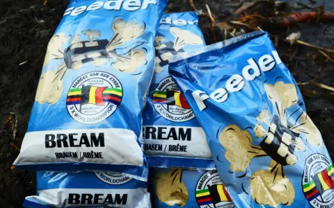 Kilka opakowań zanęt na leszcza "Feeder" z wizerunkiem belgijskiej flagi i napisem "3 x World Champion".