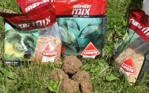 Kilka opakowań zanęta wędkarska 10kg i kulki proteinowe na trawie.