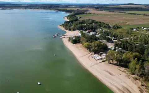 Piękny widok na Mietków Zalew z piaszczystą plażą, mariną i zielonymi terenami. Idealne miejsce na wypoczynek.