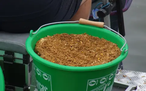 Zielone wiadro z zanętą wędkarską 25kg, gotowe do akcji.