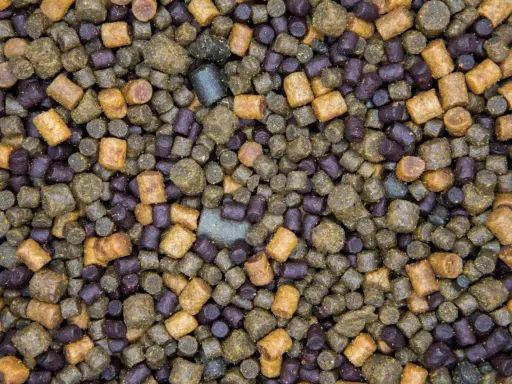 Zbliżenie na mieszankę zanęty na karpia 10 kg. Granulki w kolorach brązowym i fioletowym tworzą bogatą kompozycję.