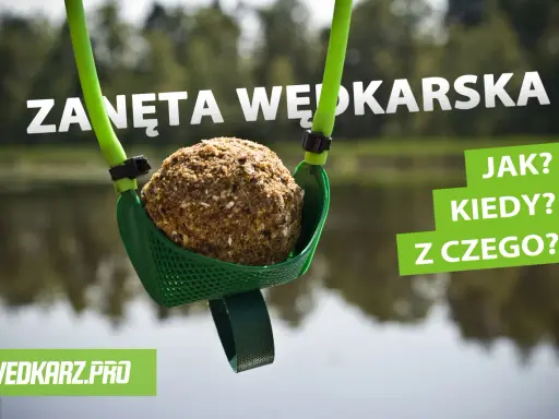 Kula zanęty wędkarskiej 5 kg w zielonej łopatce, gotowa do zarzucenia. W tle woda i drzewa.
