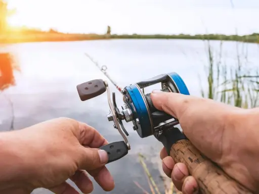 Ręce trzymające kołowrotek spinningowy. Długość wędki na spinning jest kluczowa dla komfortu łowienia.