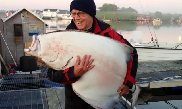 Szczęśliwy wędkarz z ogromnym halibutem. Taka zanęta halibut na jakie ryby? Na rekordowe!