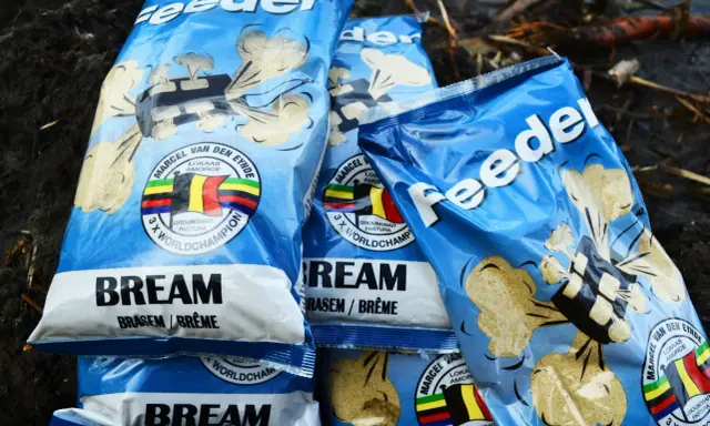 Kilka opakowań zanęt na leszcza "Feeder" z wizerunkiem belgijskiej flagi i napisem "3 x World Champion".