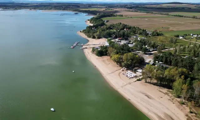 Piękny widok na Mietków Zalew z piaszczystą plażą, mariną i zielonymi terenami. Idealne miejsce na wypoczynek.