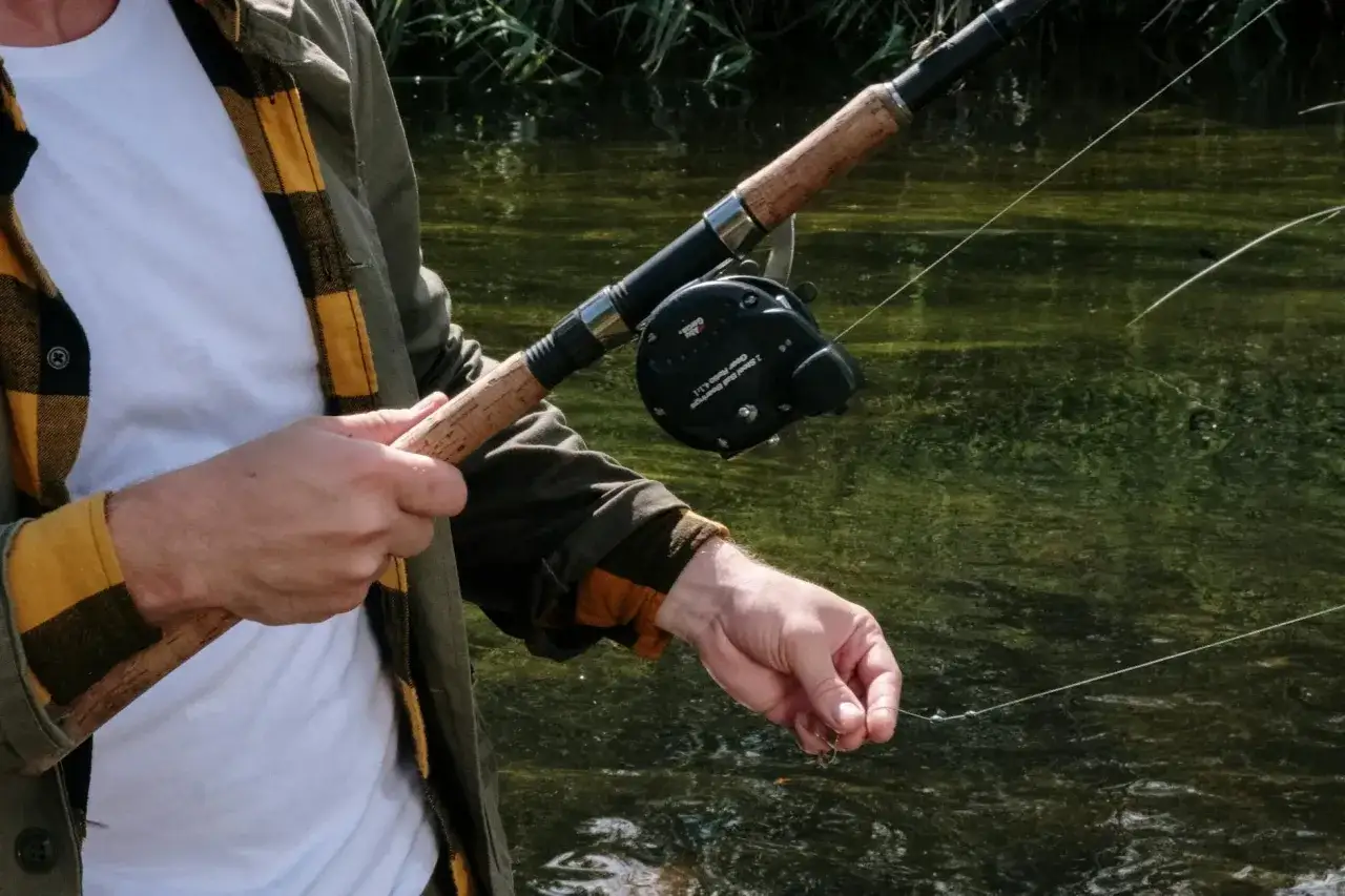 Wędkarz trzyma spinningową wędkę. Długość wędki na spinning jest kluczowa dla komfortu łowienia.