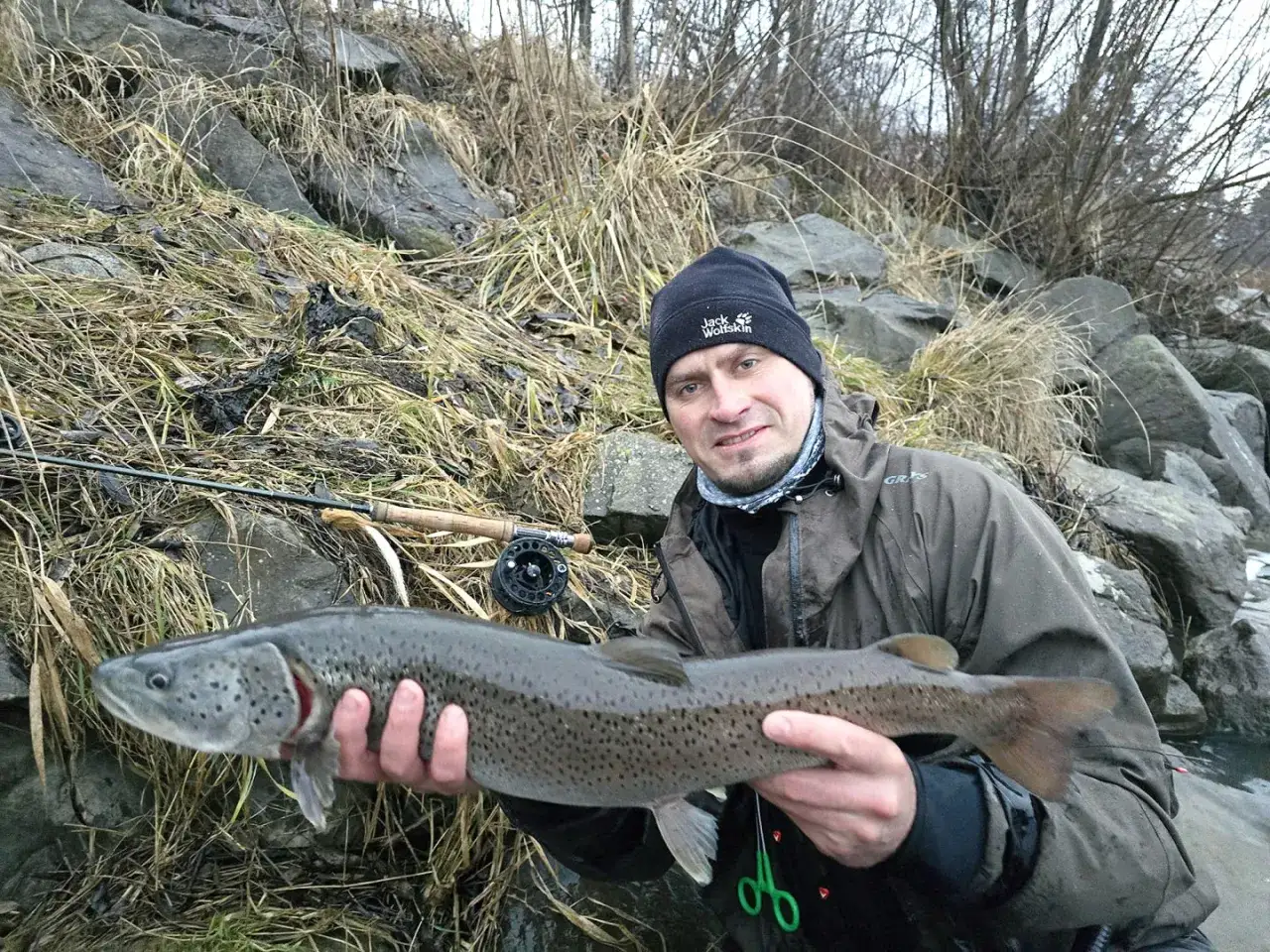 Wędkarz z pstrągiem, dowód na to, jakie ryby biorą w marcu.