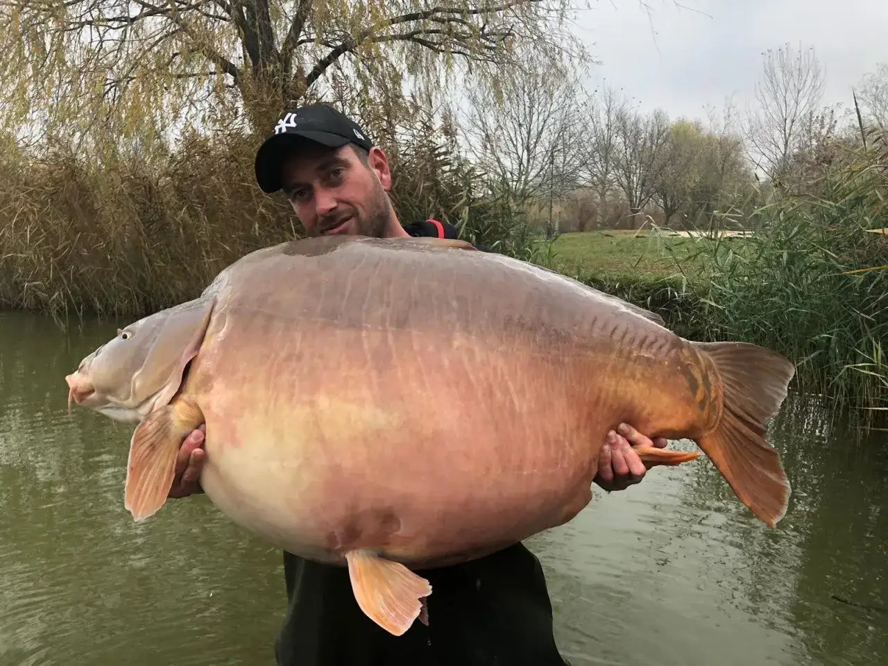 Wędkarz z ogromnym karpiem. Sprawdź euro aqua cennik, by złowić taką rybę!