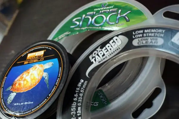 Wybór między żyłką a plecionką to kluczowa decyzja wędkarza. Na zdjęciu widać różne rodzaje żyłek, w tym PB Products Shield i Fox Tapered Mono Leaders.
